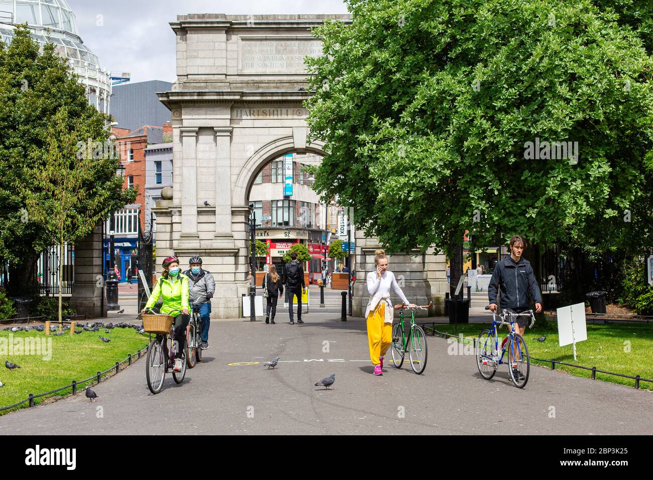 Personen mit Fahrrädern, die Gesichtsmasken tragen, betreten den St.Stephen`s Green Park in Dublin, der während der COVID-19-Pandemie die sozialen Distanzierungsregeln einhält. Stockfoto